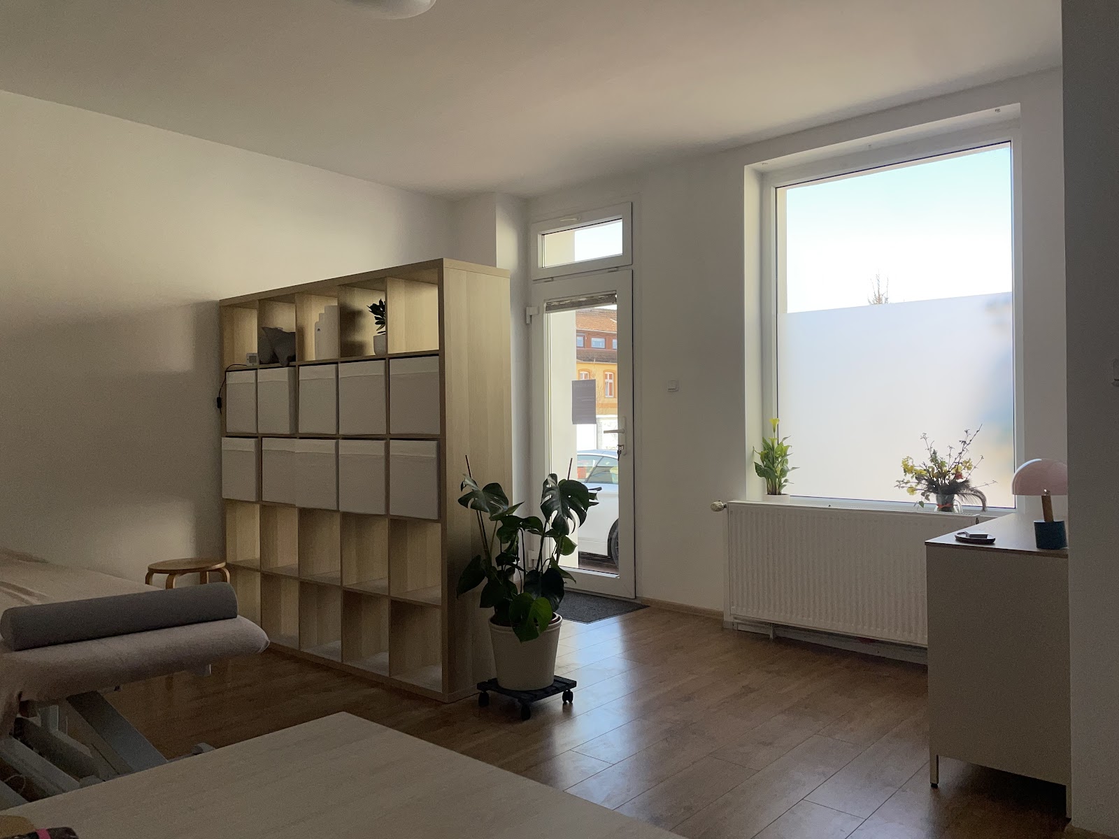 Praxisraum mit Regal als Raumteiler und großem Fenster zur Straße